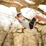 Boy sat swinging on a Lillagunga grand swing in the branches of a tall tree