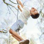Boy swinging on the Lillgunga walnut wood disco swing from a big tree