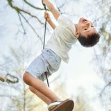 Boy swinging on the Lillgunga walnut wood disco swing from a big tree