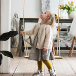 Girl stood looking up at the grand oak rope swing in a wooden living room