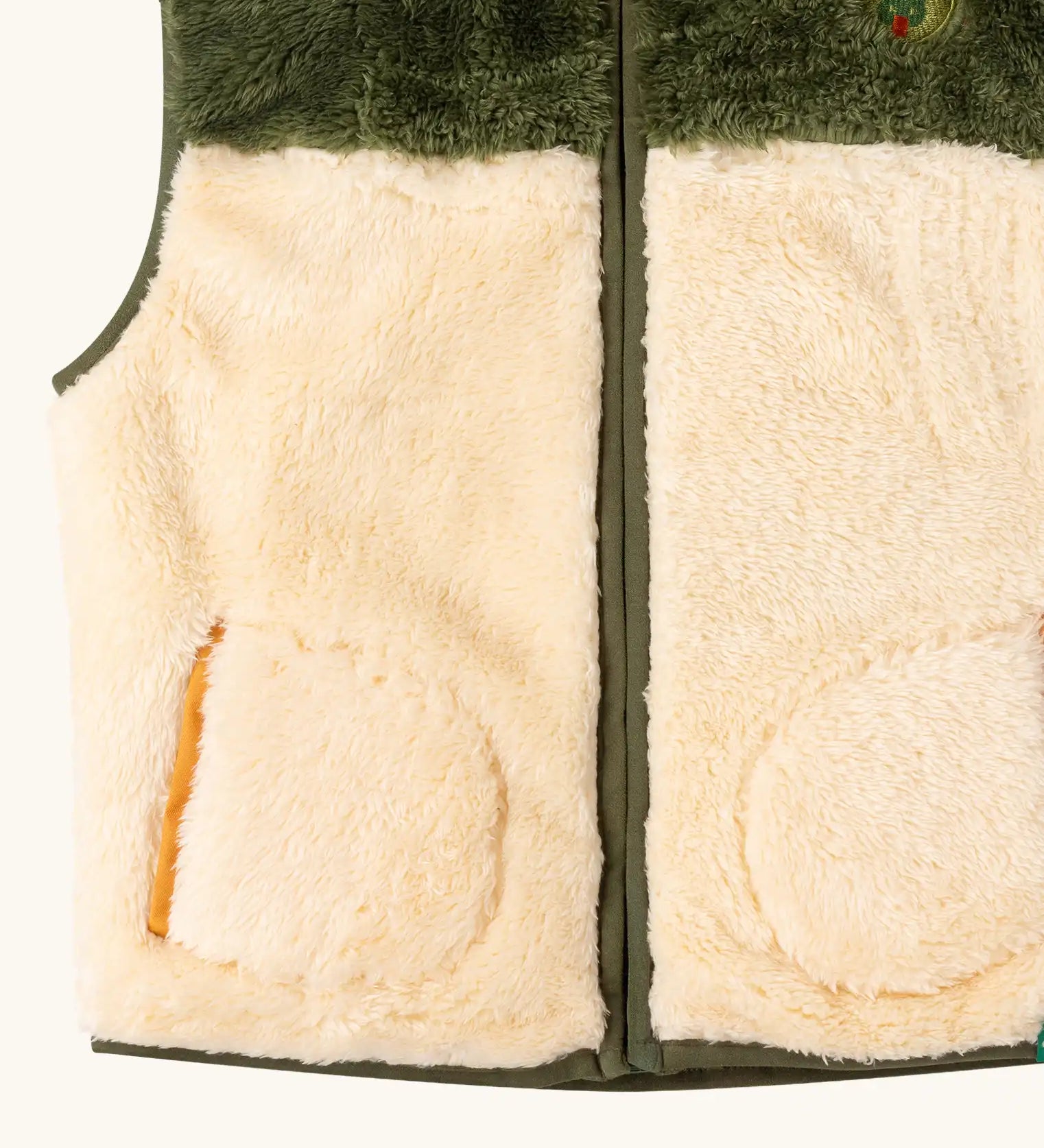 Close up of the Little Green Radicals cosy cream and chive green recycled zip-up fleece gilet.