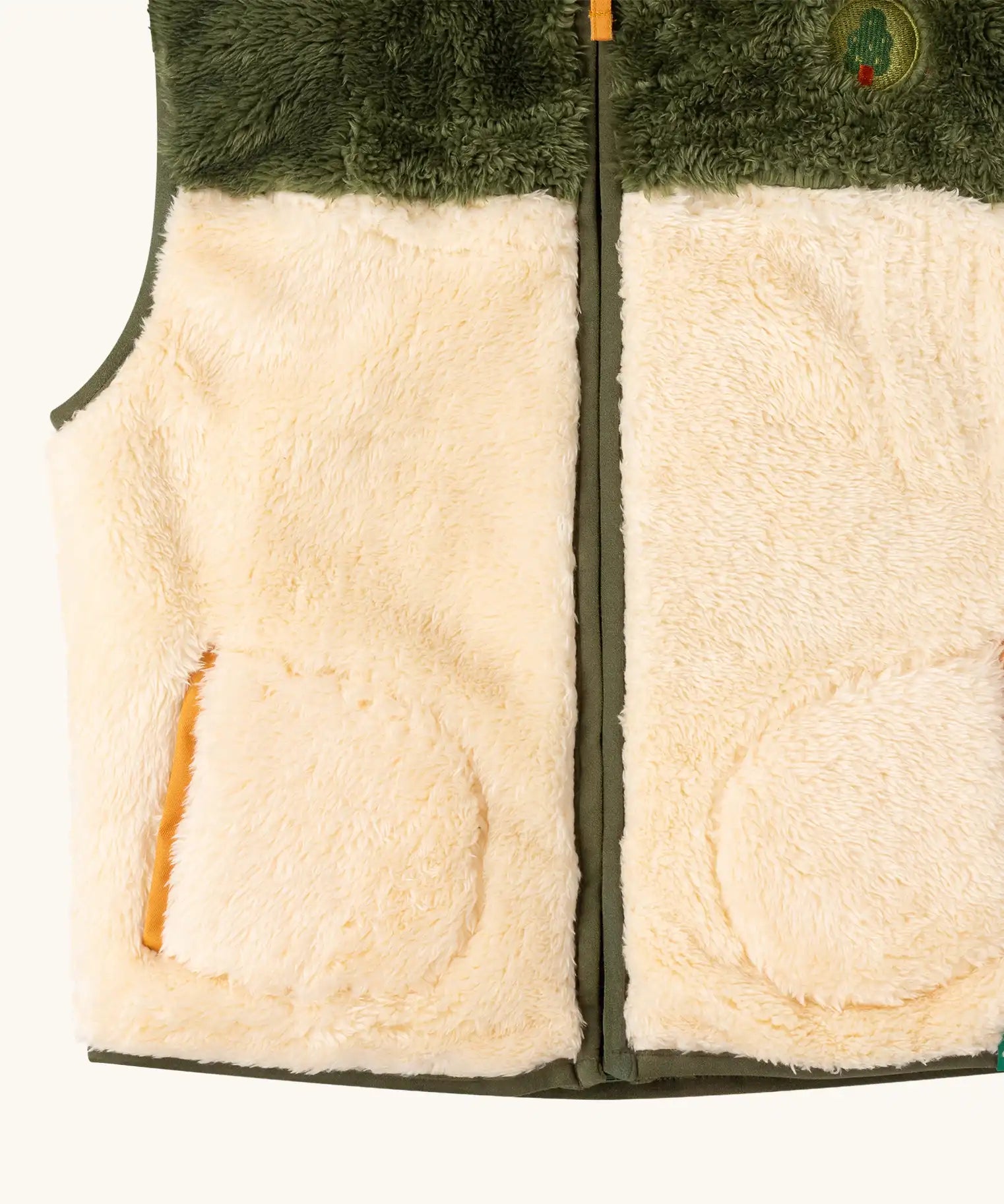 Close up of the Little Green Radicals cosy cream and chive green recycled zip-up fleece gilet.
