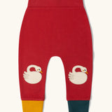 Little Green Radicals organic cotton swans knee patch joggers in red with one yellow and one dark green leg cuff.