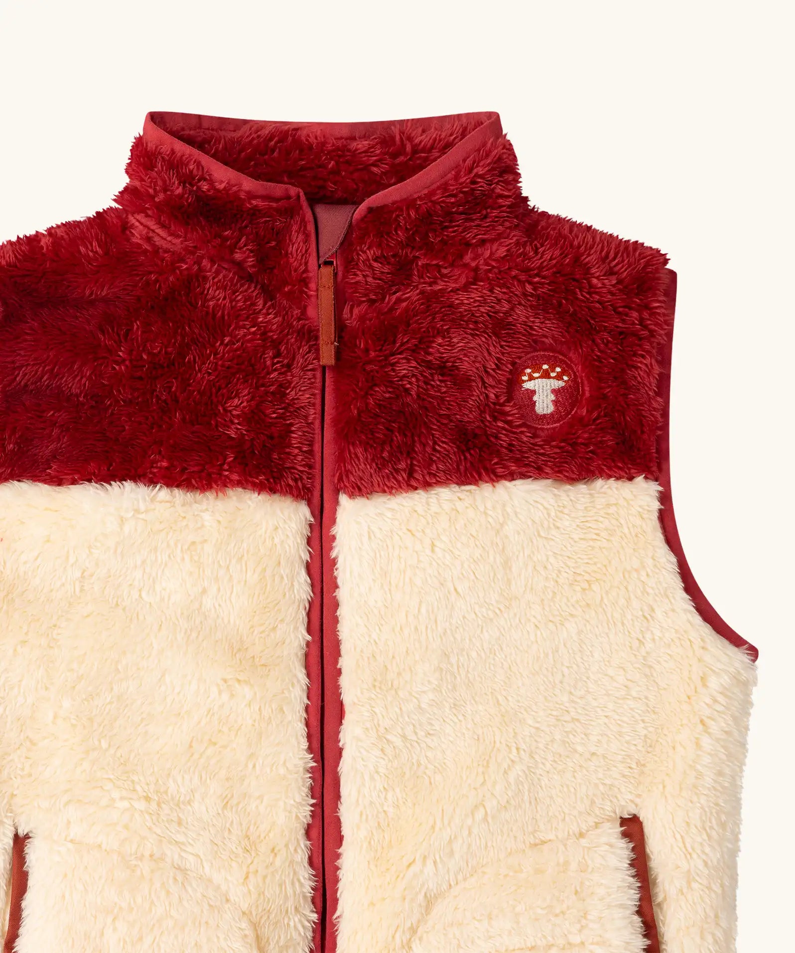 Close up of the Little Green Radicals cosy cream and plum red recycled zip-up fleece gilet.