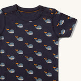 Close up of the print and top popper closure on the Little Green Radicals Adaptive Easy Feeding Whale Song T-Shirt pictured on a plain background