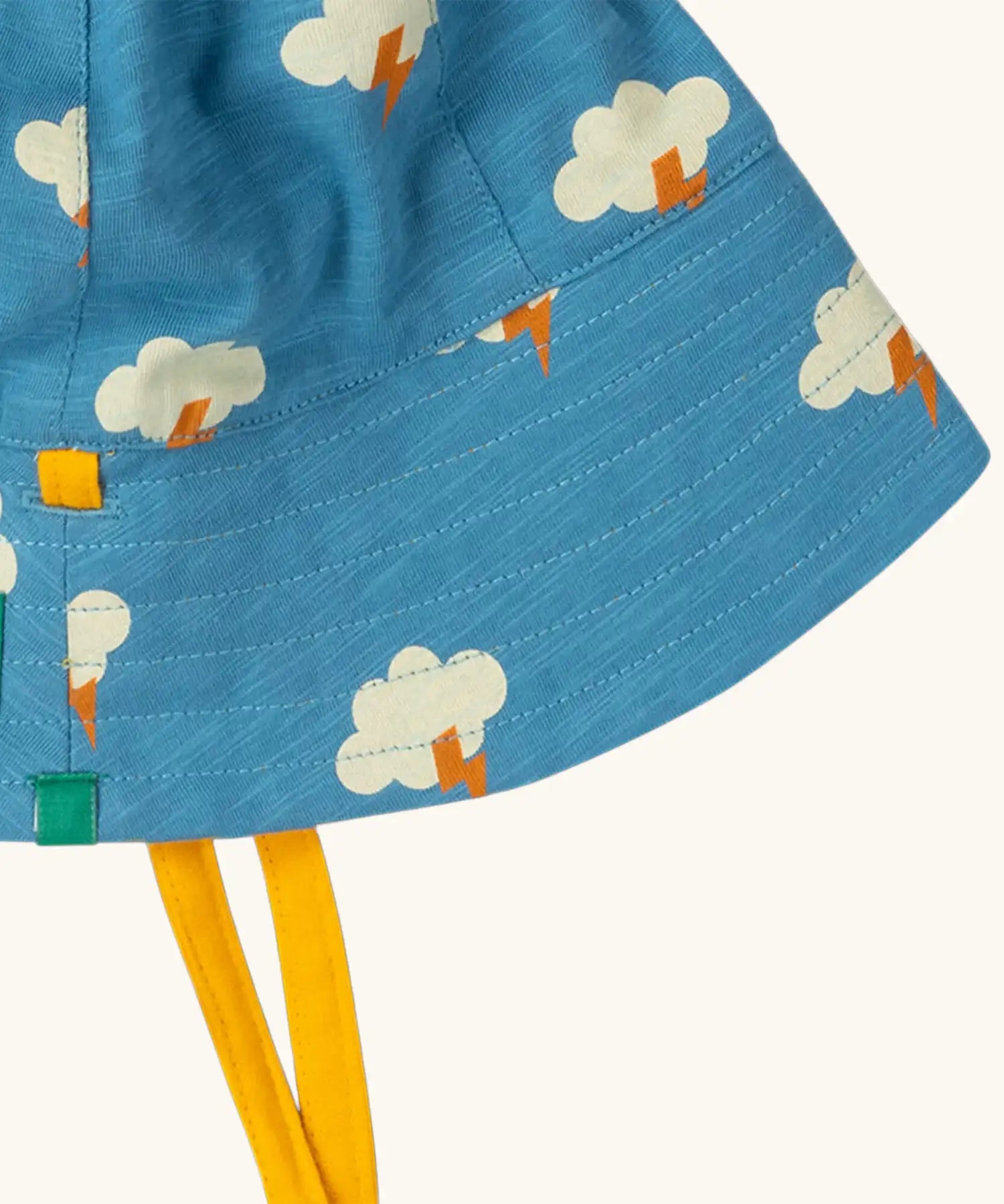 Close up of the Little Green Radicals all weather reversible children's organic cotton sunhat showing the yellow gold chin ties. 