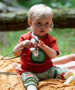 Child wearing the Little Green Radicals green apple applique organic short sleeve red t-shirt with cherry knee patch joggers.
