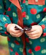Close up of the elasticated arm cuffs on the Little Green Radicals apple picking recycled waterproof children's raincoat. 