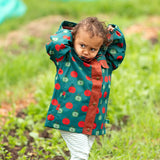 A child wearing the Little Green Radicals apple picking recycled waterproof children's raincoat with blue and cream stripes joggers.