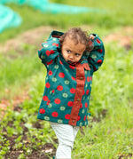 A child wearing the Little Green Radicals apple picking recycled waterproof children's raincoat with blue and cream stripes joggers.