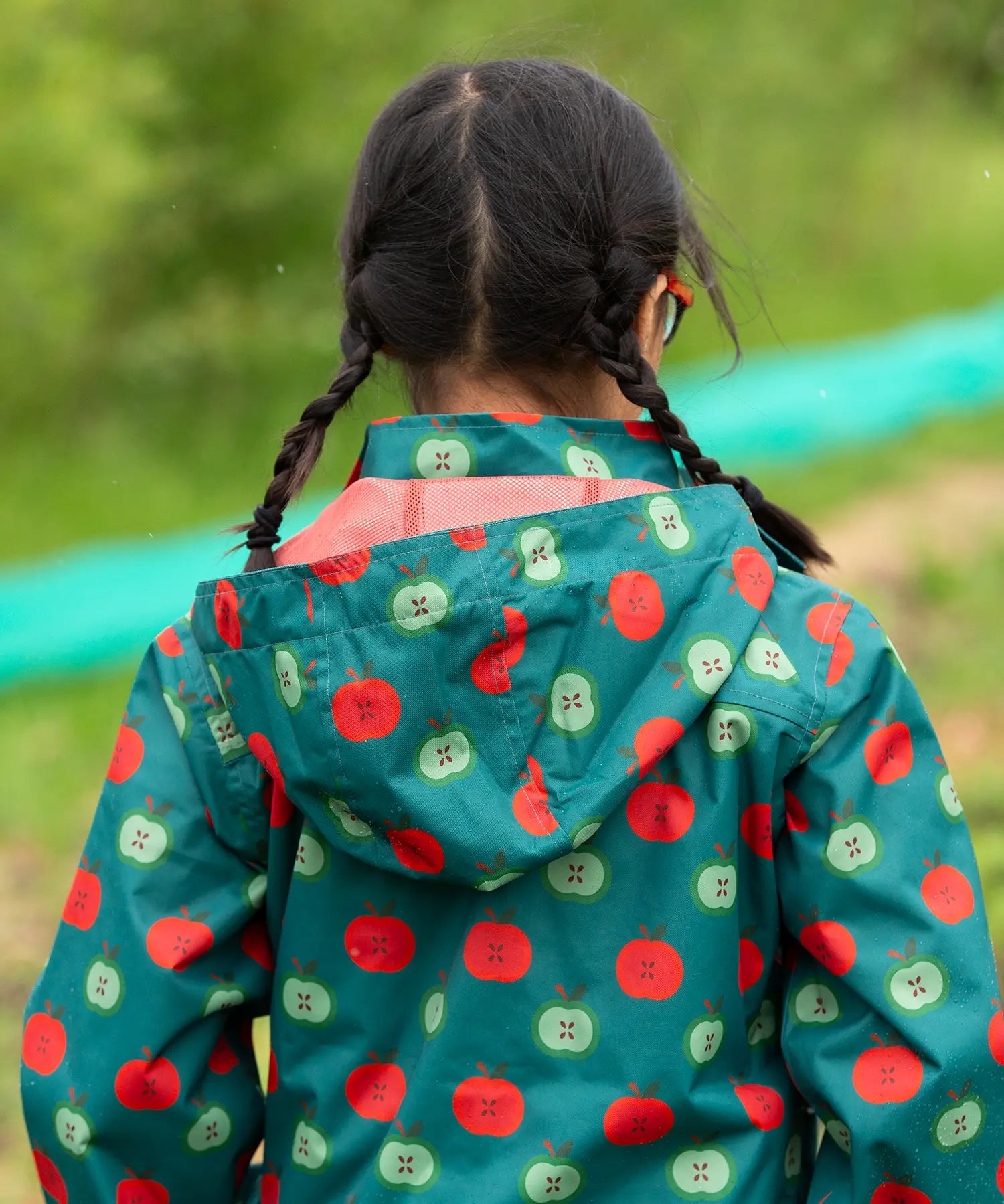 Close up of the hood on the Little Green Radicals apple picking recycled waterproof children's raincoat with a child wearing it. The hood is lined with a dark red mesh.
