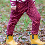 Close up of child wearing the Little Green Radicals autumn polkadot cosy cotton knee patch joggers with yellow gold wellington boots.