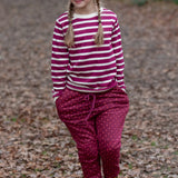Child wearing the Little Green Radicals autumn polkadot cosy cotton knee patch joggers with a striped berry long sleeve top and yellow gold wellington boots.