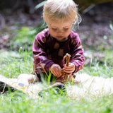 A young child sitting on grass wearing a Little Green Radicals Baby Bodysuit 2 Pack featuring a Brown Bears print. Little Green Radicals offer a range of organic cotton children's clothing available here at Babipur. 