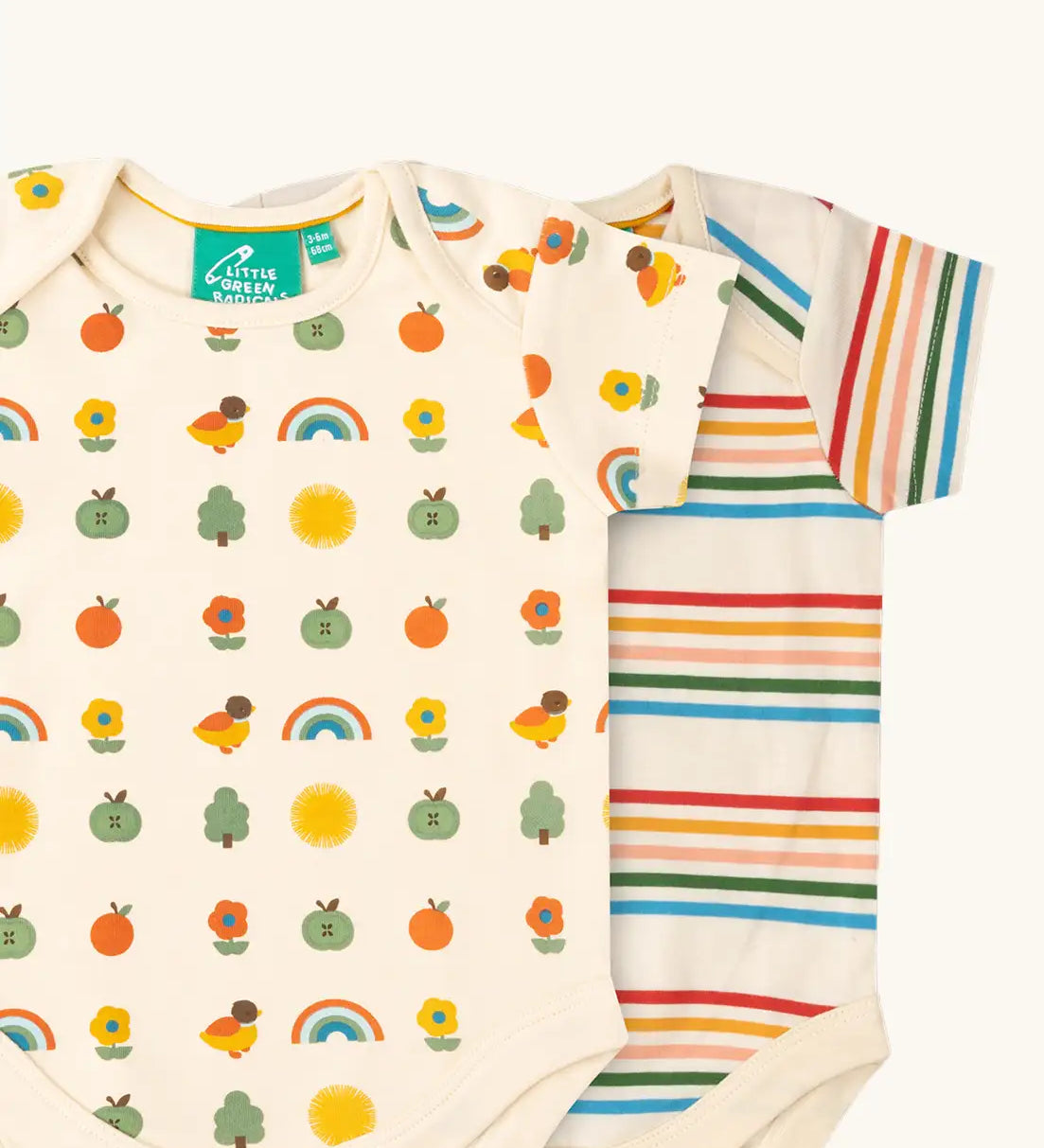 Close up of the Little Green Radicals vintage style cream rainbows organic cotton short sleeved baby bodysuit 2 Pack. One vest with a repeat nature themed print and one with a cream rainbow striped design. 