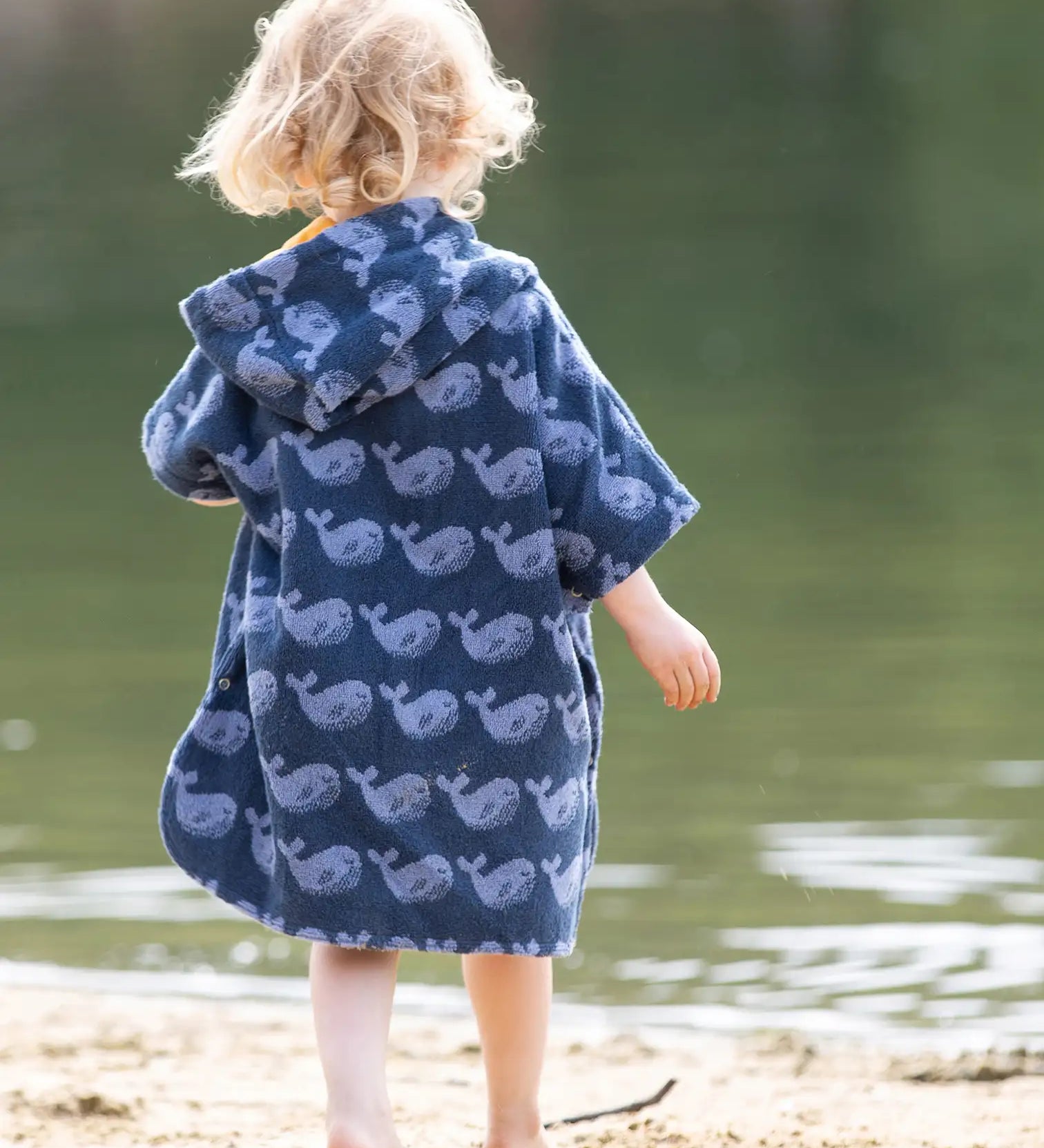 Back of child wearing the Little Green Radicals blue organic cotton Singing Whales Baby Towel Poncho.