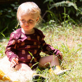 A young child sitting on grass wearing a Little Green Radicals Baby Bodysuit 2 Pack featuring a Brown Bears print. Little Green Radicals offer a range of organic cotton children's clothing available here at Babipur. 