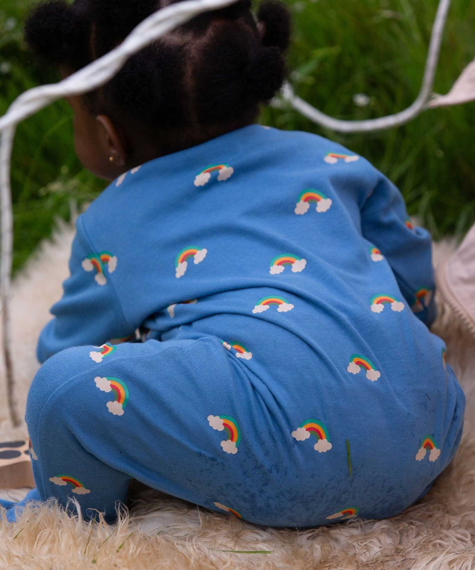 A baby wearing the Little Green Radicals Blue Rainbows Zip Organic Babygrow. The baby is facing away from the camera. Little green Radicals have a wide range of organic cotton, Fairtrade clothing and outerwear for babies and children available here at Babipur.
