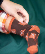 A close up of the Little Green Radicals brown teddy bear organic cotton socks on a child's feet. These socks are part of a wide range of organic cotton clothing and accessories for children available here at Babipur. 
