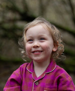 Child wearing the Little Green Radicals berry pink check classic pyjamas.