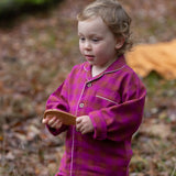 Child wearing the Little Green Radicals berry pink check classic pyjamas.