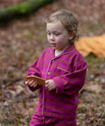 Child wearing the Little Green Radicals berry pink check classic pyjamas.