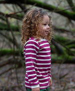 Child wearing the Little Green Radicals berry purple striped long sleeve top. 