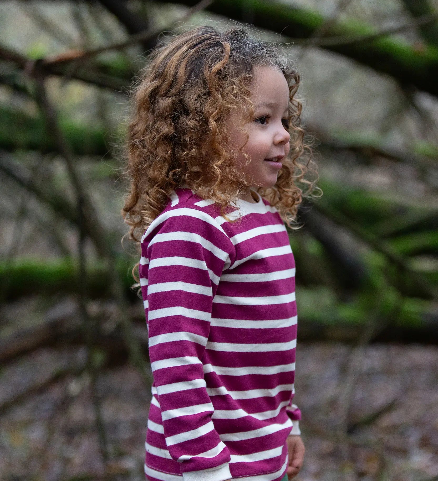 Child wearing the Little Green Radicals berry purple striped long sleeve top. 