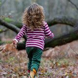 Child wearing the Little Green Radicals berry purple striped long sleeve top with green joggers.