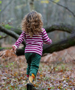 Child wearing the Little Green Radicals berry purple striped long sleeve top with green joggers.