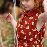 Close up of button up front on the Little Green Radicals child's red repeated spring birds print collared pinafore dress worn by a child. 