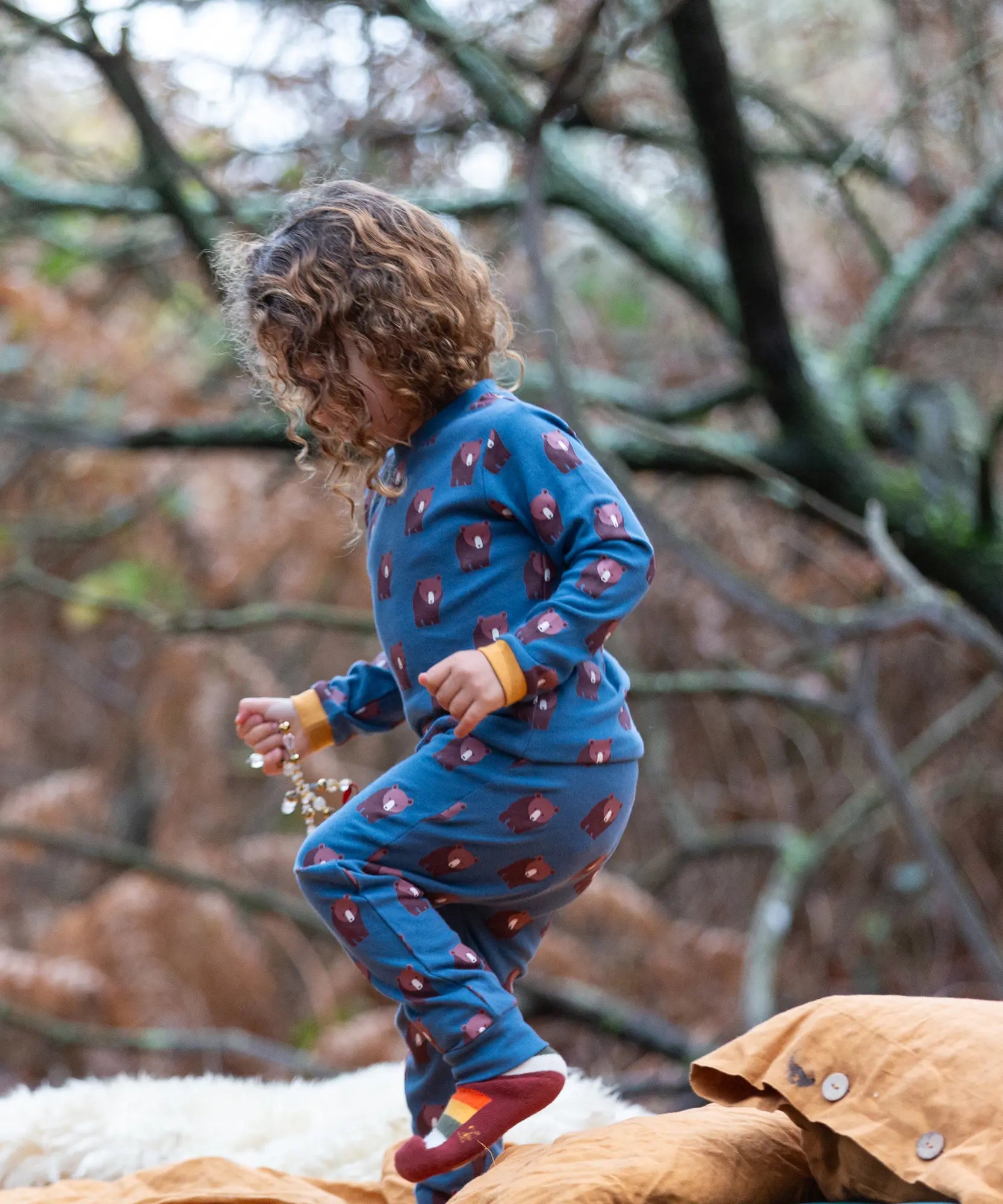 Child wearing Little Green Radicals  blue bears organic cotton pyjamas and striped socks. 