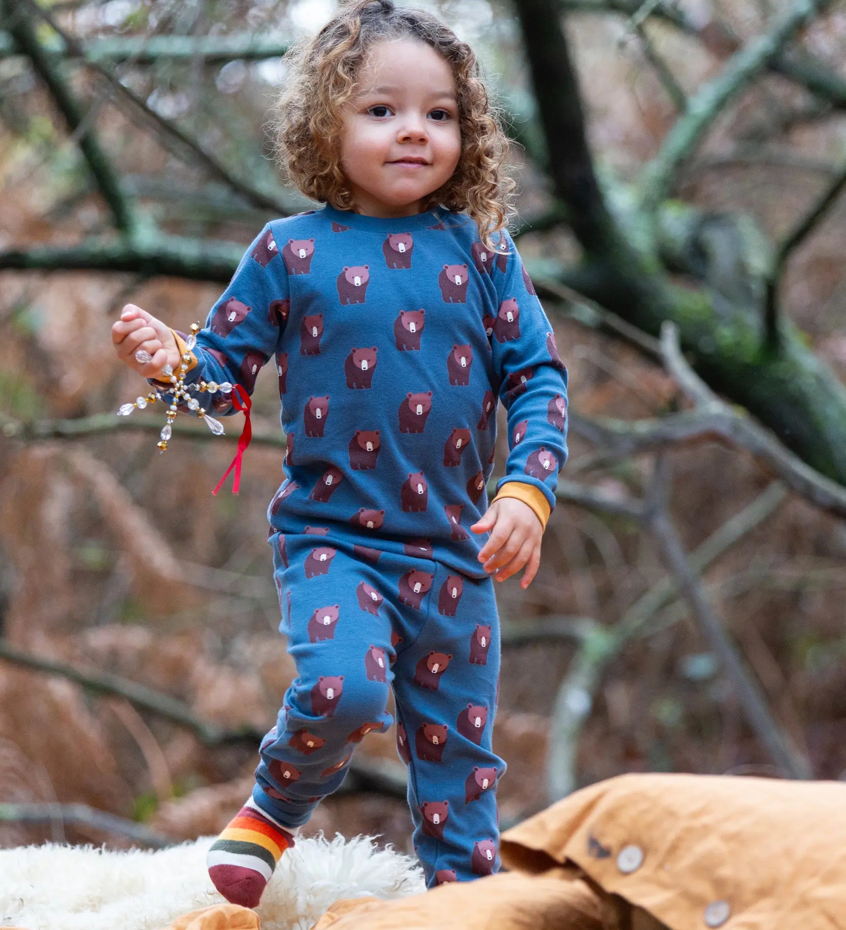 Child wearing Little Green Radicals  blue bears organic cotton pyjamas and striped socks. 