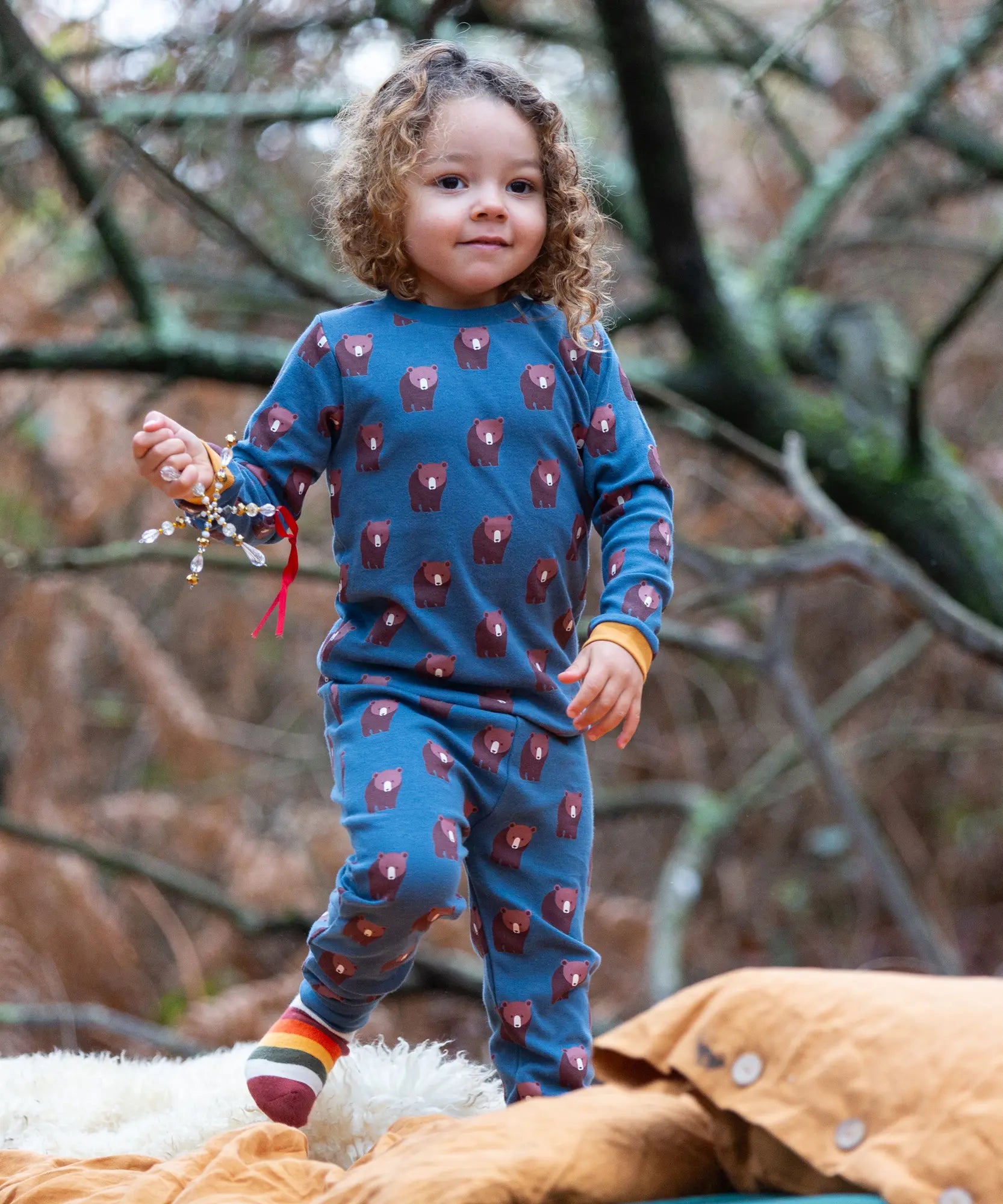 Child wearing Little Green Radicals  blue bears organic cotton pyjamas and striped socks. 