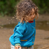 A child wearing the Little Green Radicals From One To Another Deep Blue Colour Block Knitted Cardigan. This organic cotton cardigan is part of a wide range of organic cotton, Fairtrade children's clothing and outerwear available here at Babipur.