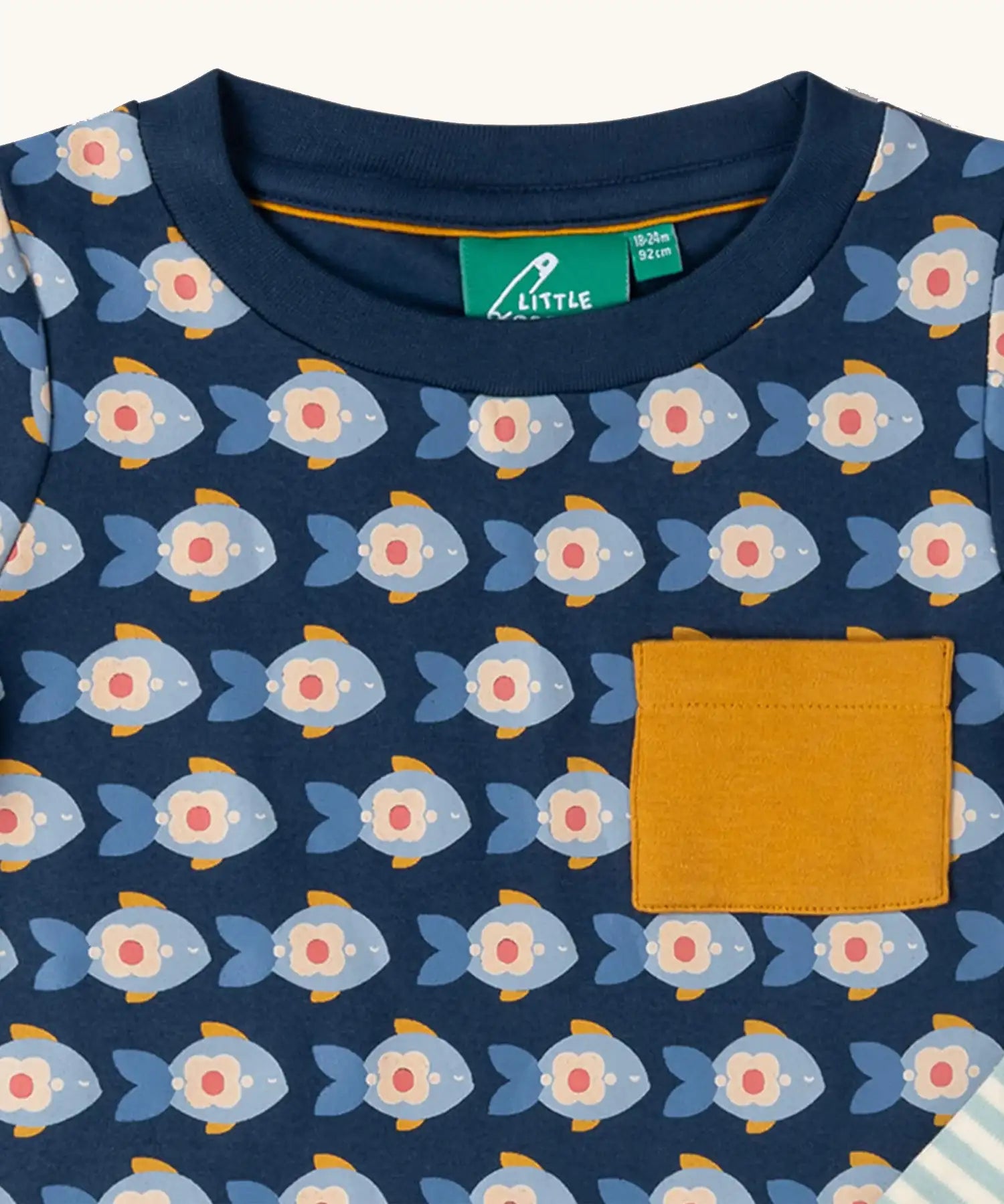 Close up of the Little Green Radicals little fish organic cotton t-shirt from the playset. A navy top with repeat fish print and a yellow chest pocket.
