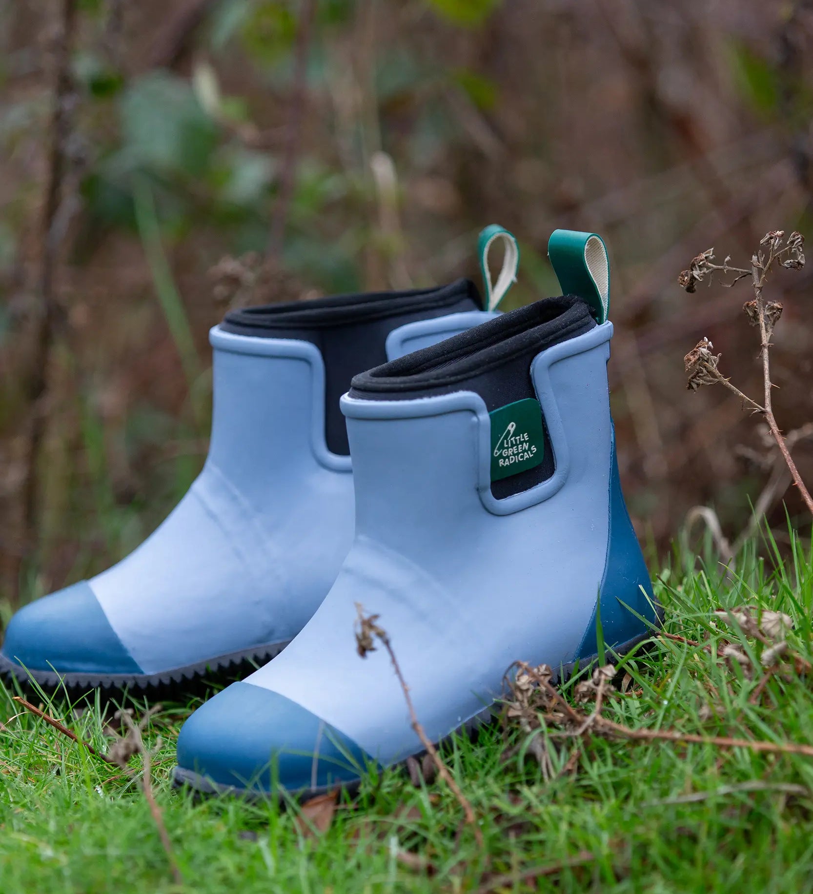 Little Green Radicals soft blue natural rubber ankle rain wellington boots placed on grass.