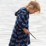 Side view of a child wearing the Little Green Radicals organic cotton Singing Whales Baby Towel Poncho.