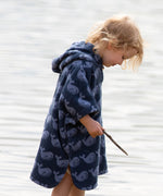 Side view of a child wearing the Little Green Radicals organic cotton Singing Whales Baby Towel Poncho.