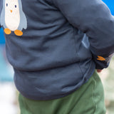 Close up of a child wearing the Little Green Radicals blue penguins applique long sleeve organic cotton top in navy.