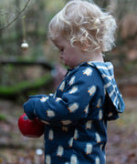 Child wearing a Little Green Radicals navy blue penguins hooded reversible snug suit. One side has a penguin print, the other is striped. 