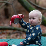 Baby wearing the Little Green Radicals blue penguins GOTS organic cotton zip up babygrow sitting on a green blanket outdoors. Navy blue coloured cotton with an all over penguin print.