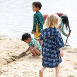 Back of a child wearing the Little Green Radicals clue singing whale kids organic cotton towel poncho. 