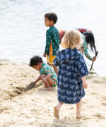 Back of a child wearing the Little Green Radicals clue singing whale kids organic cotton towel poncho. 