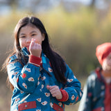 Child wearing a Little Green Radicals blue sun birds recycled waterproof adventure Winter coat.