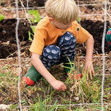 Child wearing the Little Green Radicals navy singing whales print comfy organic cotton joggers with a yellow muslin henley t-shirt and green and red wellingtons.