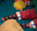 A close up of the Little Green Radicals brown teddy bear organic cotton socks on a child's feet. These socks are part of a wide range of organic cotton clothing and accessories for children available here at Babipur. 