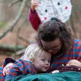 Woman wearing the Little Green Radicals burnt ochre check adult organic cotton classic pyjamas cudling a child wearing matching pyjamas.