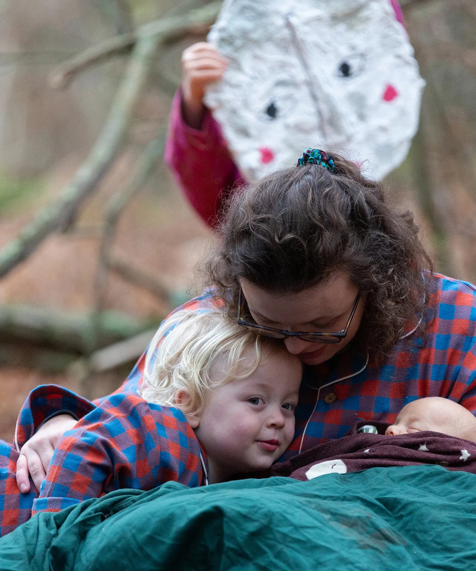 Woman wearing the Little Green Radicals burnt ochre check adult organic cotton classic pyjamas cudling a child wearing matching pyjamas.