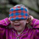 Child holding the Little Green Radicals  burnt ochre blue check organic cotton adult eye mask.